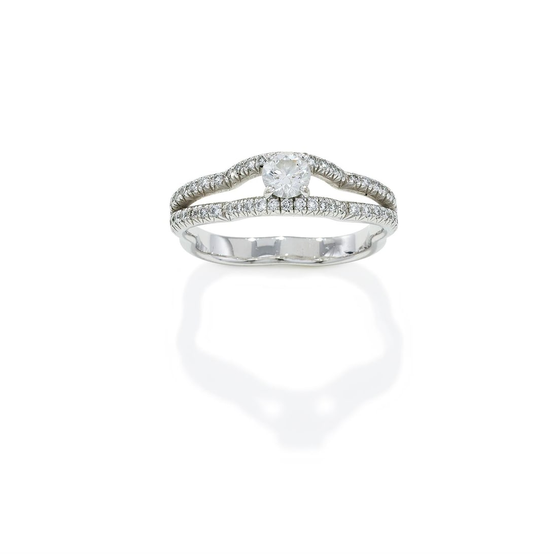 CHANEL, A DIAMOND 'CAMÉLIA' RING: CHANEL, A DIAMOND 'CAMÉLIA' RING The camelia shaped 18ct white gold band with brilliant cut diamond set bifurcated shoulders, to a central brilliant cut diamond, weighing 0.32 carats, signed Chan