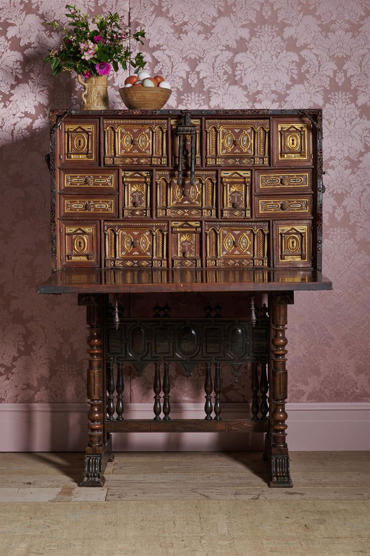 A SPANISH WALNUT, WROUGHT IRON AND PARCEL GILT VARGUENO ON STAND, 18TH CENTURY: A SPANISH WALNUT, WROUGHT IRON AND PARCEL GILT VARGUENO ON STAND 18TH CENTURYThe hinged fall opening to an arrangement of drawers of various size, incorporating velvet detailing to some of the iron mo