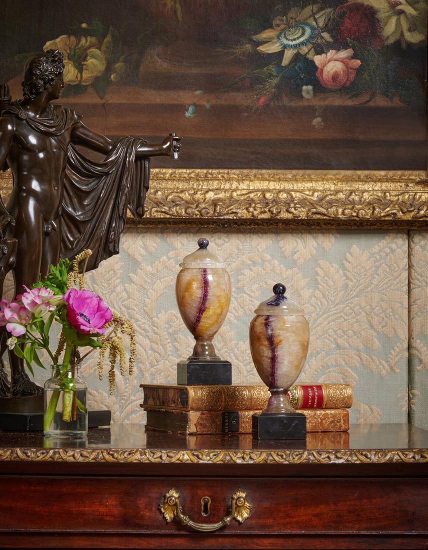 A PAIR OF LATE GEORGE III BLUE JOHN URNS, CIRCA 1810: A PAIR OF LATE GEORGE III BLUE JOHN URNSCIRCA 1810Each fashioned probably from 'Winnats One Vein' Blue John, the lids above hollow bodies, on black Ashford marble bases 18cm high, the bases 5.5cm squa