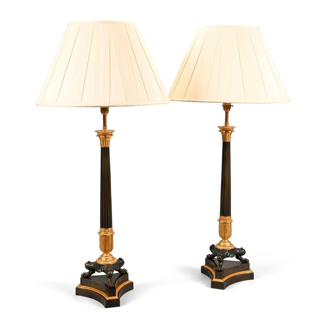 A LARGE PAIR OF GILT AND PATINATED BRONZE TRIFORM TABLE LIGHTS, EARLY 19TH CENTURY: A LARGE PAIR OF GILT AND PATINATED BRONZE TRIFORM TABLE LIGHTS EARLY 19TH CENTURY Later fitted for electricity 58.5cm high to the top of the column94cm high including the shade