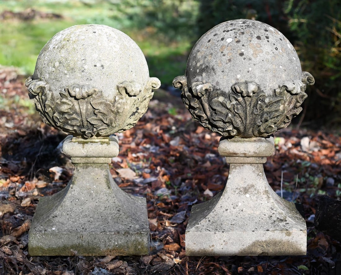 A PAIR OF COMPOSITION STONE GATEPOST BALL FINIALS, CONTEMPORARY: A PAIR OF COMPOSITION STONE GATEPOST BALL FINIALS CONTEMPORARY Of leaf decorated ball form, with swept bases 70cm high, the bases 33cm square
