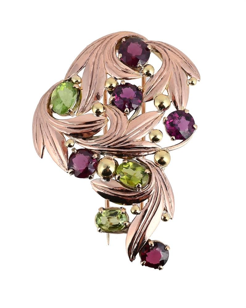A PERIDOT AND GARNET SPRAY BROOCH: A PERIDOT AND GARNET SPRAY BROOCH The oval cut peridots and circular cut garnets within a polished veined leaf spray setting, double pin setting, stamped 9ct B.I Size/dimensions: