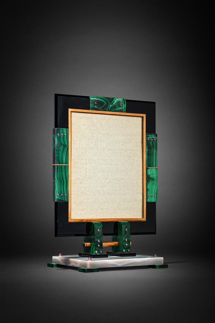 OSTERTAG (PARIS), AN ART DECO MALACHITE, ONYX AND ENAMEL PICTURE FRAME, CIRCA 1934: OSTERTAG (PARIS)AN ART DECO MALACHITE, ONYX AND ENAMEL PICTURE FRAME, CIRCA 1934The rectangular bevelled-edge black onyx frame, enhanced at the top and sides by malachite plaques with gold detail, the