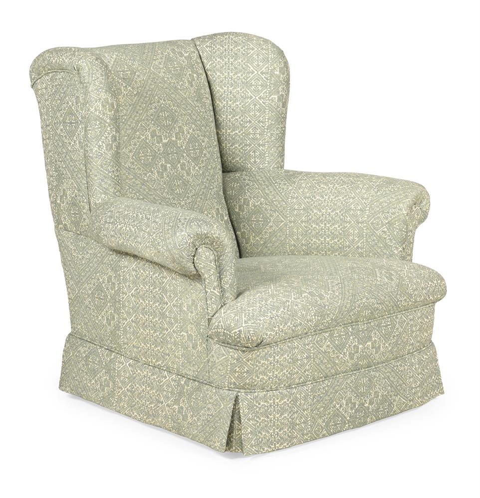 AN EDWARDIAN BEECH AND GUY GOODFELLOW UPHOLSTERED WINGBACK ARMCHAIR, FIRST QUARTER 20TH CENTURY: AN EDWARDIAN BEECH WINGBACK ARMCHAIR FIRST QUARTER 20TH CENTURY Upholstered in Guy Goodfellow 'Emerald Fez' fabric with bun for supports and recessed castors 92cm high, 95cm wide, 95cm deep