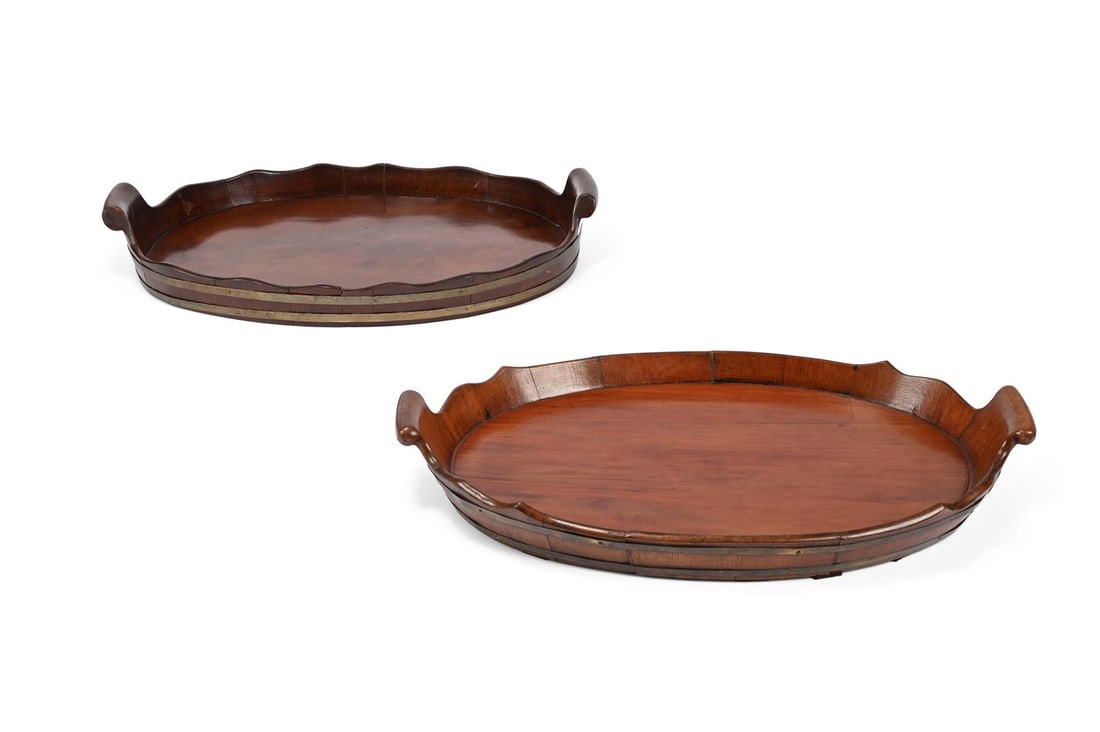 A COOPERED MAHOGANY AND BRASS BOUND OVAL TRAY, EARLY 19TH CENTURY, AND ANOTHER SIMILAR: A COOPERED MAHOGANY AND BRASS BOUND OVAL TRAY POSSIBLY DUTCH, EARLY 19TH CENTURY With two volute handles, 56cm in length TOGETHER WITH Another similar tray, probably later, 57.5cm in length Condition