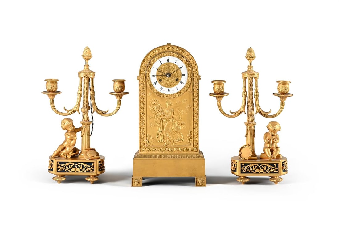 A FRENCH EMPIRE ORMOLU CLOCK CASE AND DIAL AND A PAIR OF CANDELABRA, EARLY 19TH CENTURY AND LATER (1 of 3)