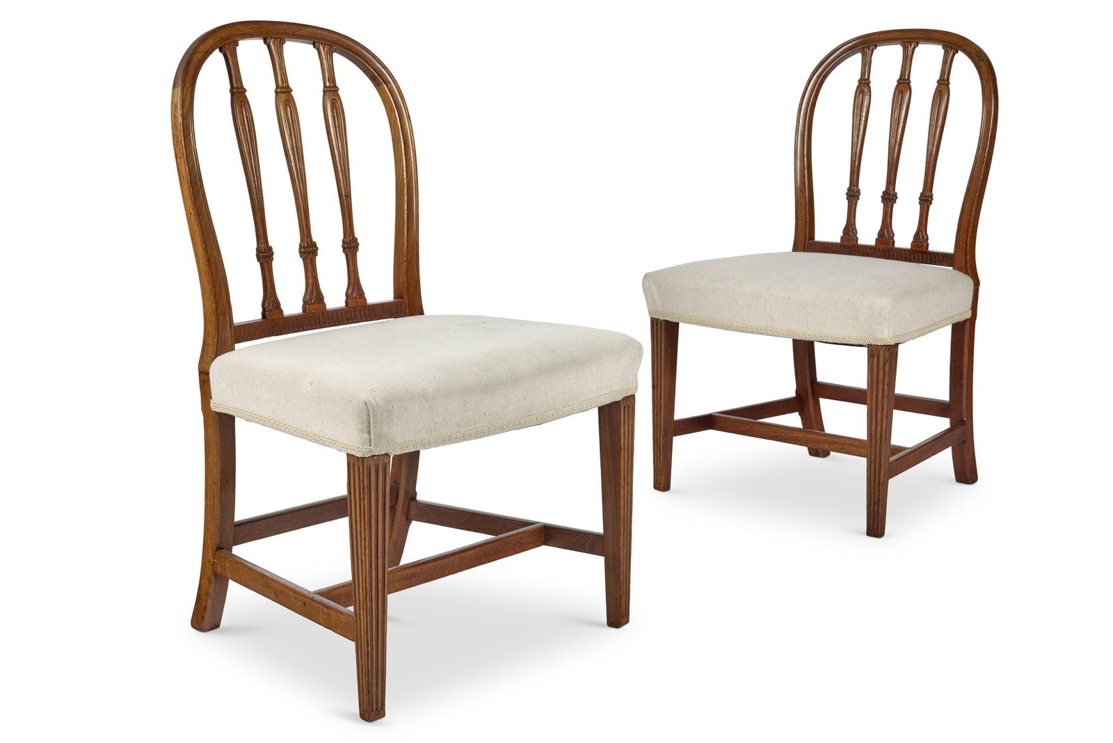 A PAIR OF GEORGE III MAHOGANY CHAIRS, ATTRIBUTED TO GILLOWS, CIRCA 1790: A PAIR OF GEORGE III MAHOGANY CHAIRSATTRIBUTED TO GILLOWS, CIRCA 1790Each with an arched back and three slender leaf-carved upright splats above a padded seat on fluted square tapering legs joined by