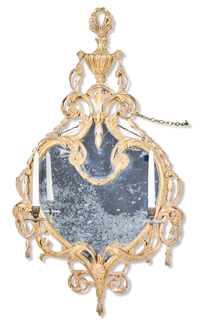 A GEORGE III GILTWOOD GIRANDOLE, CIRCA 1765, IN THE MANNER OF FRANCE & BRADBURN: A GEORGE III GILTWOOD GIRANDOLE CIRCA 1765, IN THE MANNER OF FRANCE & BRADBURNWith a cartouche shaped plate within a carved, pierced and scrolled surround surmounted by a classical urn with rams' mask