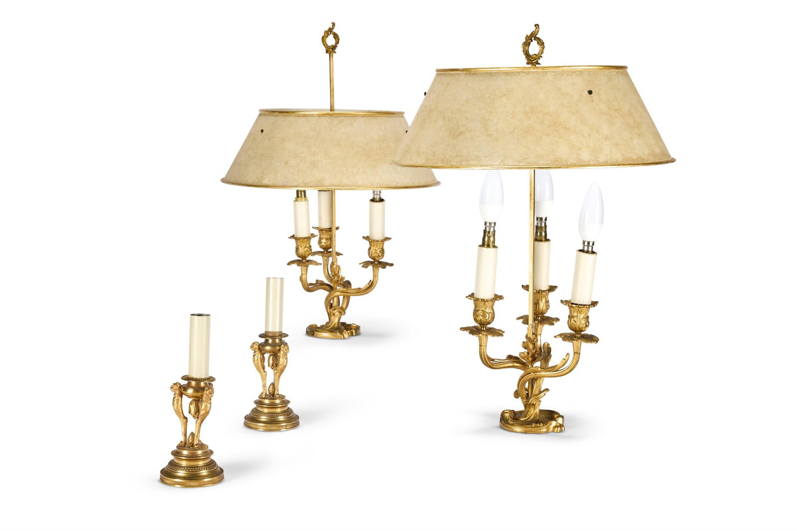 A PAIR OF ORMOLU THREE BRANCH ROCOCO BOUILLOTTE TABLE LIGHTS, FRENCH, LATE 19TH CENTURY: A PAIR OF ORMOLU THREE BRANCH ROCOCO BOUILLOTTE TABLE LIGHTS FRENCH, LATE 19TH CENTURY Stamped 'B.P & CIE', now fitted for electricity, with cream painted tole shades 57cm high Together with a pair of