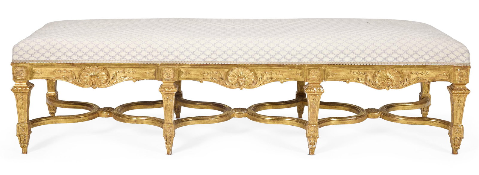 A GILTWOOD STOOL OF LOUIS XIV STYLE, CIRCA 1900, POSSIBLY BY LENYGON & MORANT: A GILTWOOD STOOL OF LOUIS XIV STYLECIRCA 1900, POSSIBLY BY LENYGON & MORANTWith padded rectangular seat, the rails carved with scallop shells and scrolling foliage, on fluted square tapering legs with