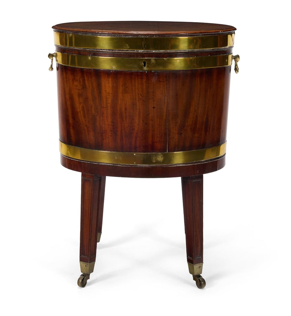 A GEORGE III MAHOGANY AND BRASS BOUND OVAL CELLARET, CIRCA 1770: A GEORGE III MAHOGANY AND BRASS BOUND OVAL CELLARETCIRCA 1770Of tapered form, with a moulded top and divided lead-lined interior, the sides with brass handles, on square legs and brass castors, the st