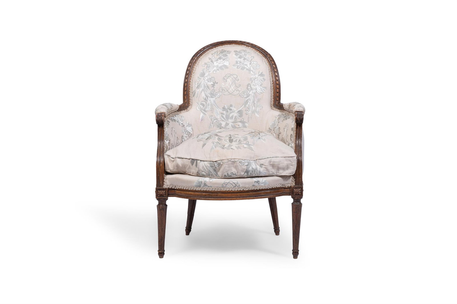 A LOUIS XVI STAINED BEECH BERGÈRE, CIRCA 1780: A LOUIS XVI STAINED BEECH BERGÈRECIRCA 1780With an arched ribbon carved back and padded arms with scrolled terminals above a bowed seat, upholstered in silk embroidered linen, on tapering turned 