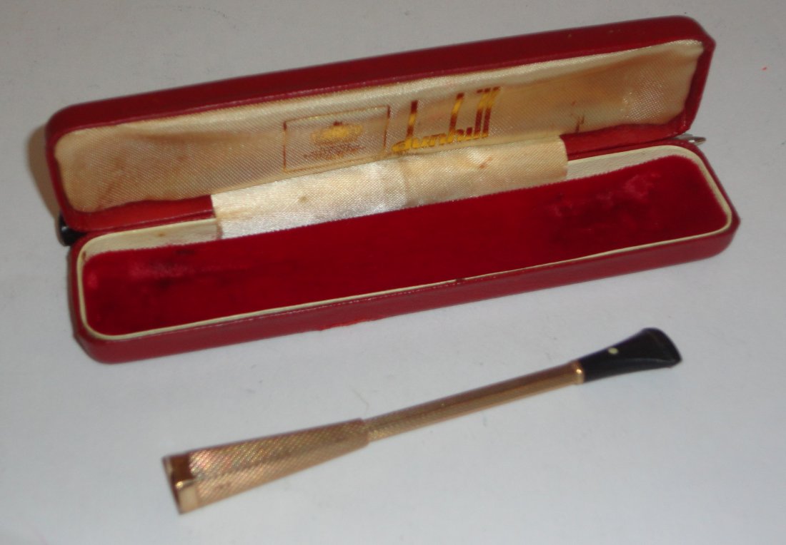 A 9 carat gold Dunhill cigarette holder, by Alfred: A 9 carat gold Dunhill cigarette holder, by Alfred Dunhill, Birmingham 1969, all over engine turned decoration, hexagonal outline end with ejecting action, with black plastic mouthpiece, 9.8c