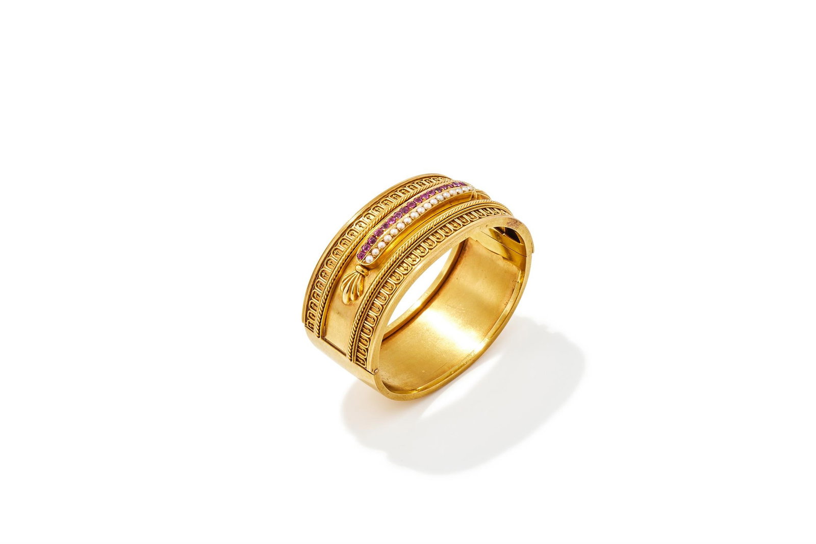 AN ARCHAEOLOGICAL REVIVAL RUBY AND SPLIT PEARL BANGLE: AN ARCHAEOLOGICAL REVIVAL RUBY AND SPLIT PEARL BANGLECIRCA 1870The front with a raised panel set with a line of circular cut rubies next to a line of split pearls, between ropetwist and beadwork borde