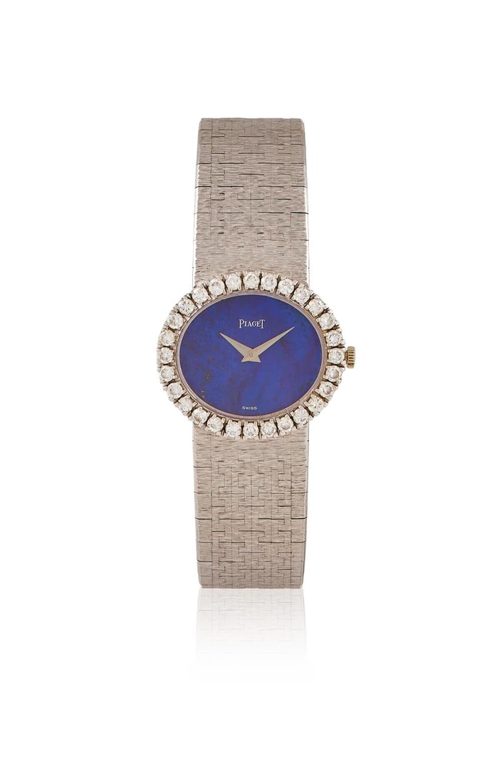 PIAGET, A LAPIS LAZULI AND DIAMOND WRISTWATCH: PIAGET, A LAPIS LAZULI AND DIAMOND WRISTWATCHThe oval lapis lazuli dial within a brilliant cut diamond bezel, case back secured by two screws, integral textured 18ct white gold Piaget bracelet, signed