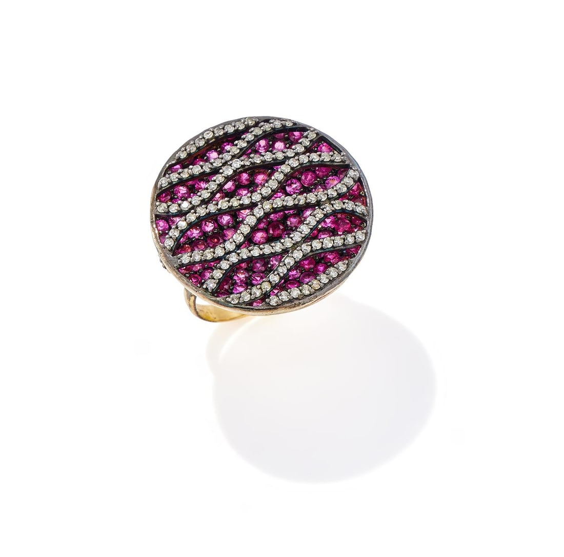 A DIAMOND AND RUBY DISC DRESS RING: A DIAMOND AND RUBY DISC DRESS RING The concave panel pavé set with circular cut rubies beneath a woven lattice set with single cut diamonds, unmarked Size/dimensions: panel 2.5cm diameter, ring