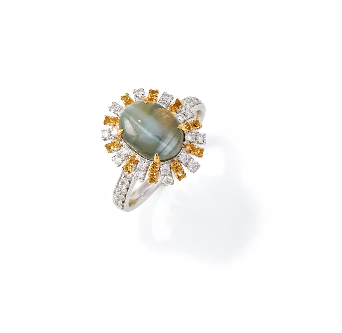 A CAT'S EYE CHRYSOBERYL AND DIAMOND CLUSTER RING: A CAT'S EYE CHRYSOBERYL AND DIAMOND CLUSTER RING The oval cabochon cat's eye chrysoberyl within a radiating brilliant cut diamond and yellow diamond surround, between diamond shoulders, stamped Pt950S
