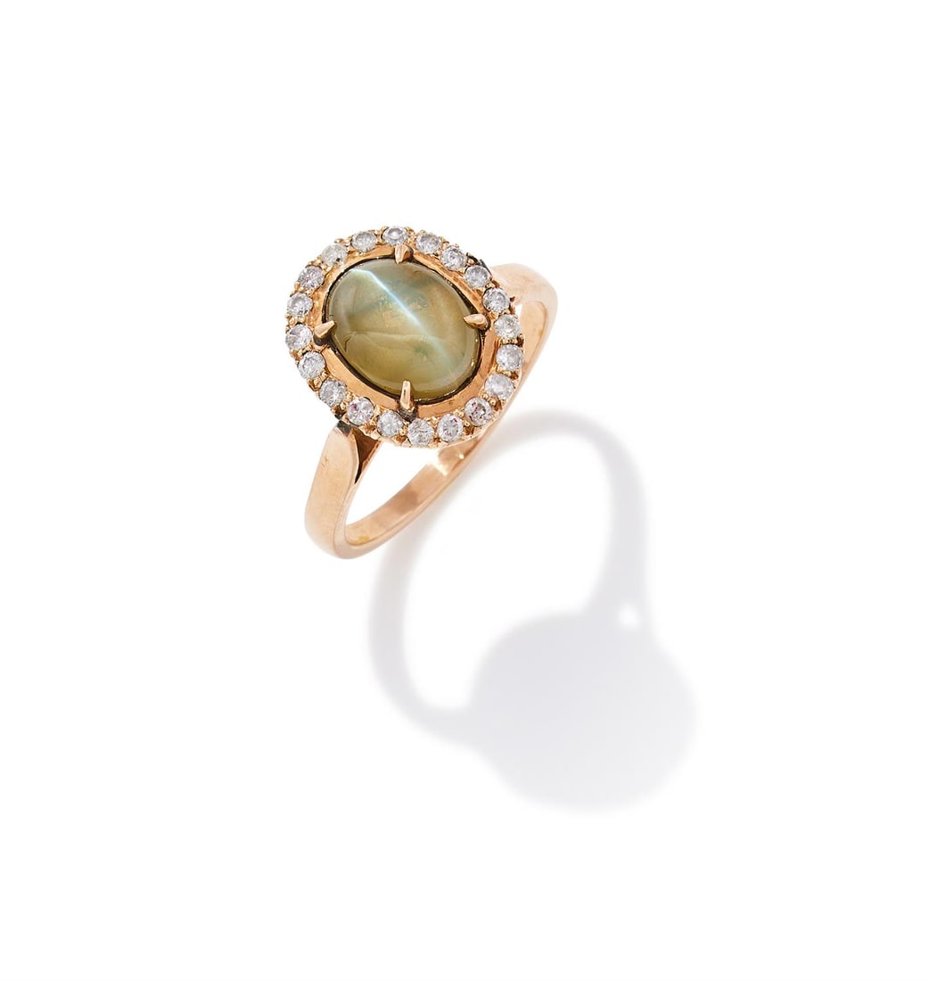 A CAT'S EYE CHRYSOBERYL AND DIAMOND CLUSTER RING: A CAT'S EYE CHRYSOBERYL AND DIAMOND CLUSTER RINGThe oval cabochon cat's eye chrysoberyl within a brilliant cut diamond surround, unmarkedSize/dimensions: ring size NGross weight: 3.9 grams