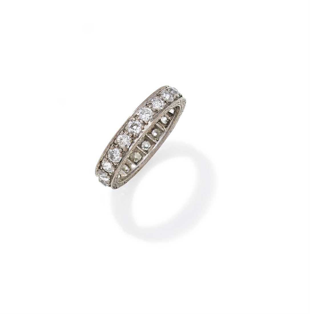 A DIAMOND ETERNITY RING: A DIAMOND ETERNITY RING Set with a continuous row of old European cut diamonds, with scrolled foliate chased sides, stamped 18ct Size/dimensions: ring size O 1/2 Gross weight: 4.6 grams