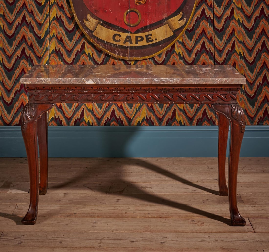 A GEORGE II CARVED MAHOGANY SIDE OR CONSOLE TABLE, IN THE MANNER OF WILLIAM KENT, CIRCA 1750: A GEORGE II CARVED MAHOGANY SIDE OR CONSOLE TABLEIN THE MANNER OF WILLIAM KENT, CIRCA 1750With a Fior di Pesco Apuano marble top76cm high, 122.5cm wide, 63cm deepFor a similar table also with a Vitruv