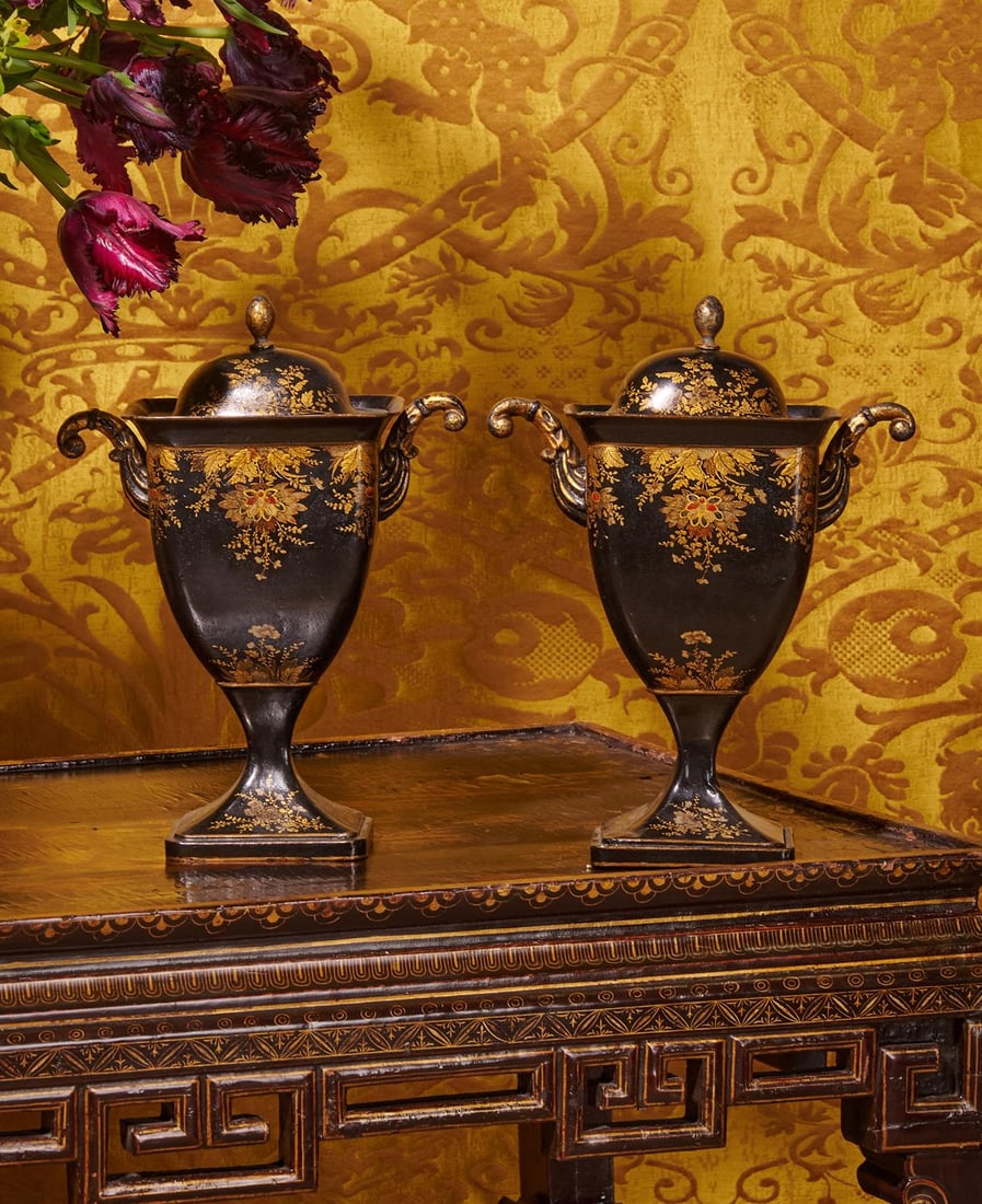A PAIR OF TOLE PEINTE CHESTNUT URNS, CIRCA 1830: A PAIR OF TOLE PEINTE CHESTNUT URNS CIRCA 1830With gilt scrolling foliate decoration with red detailing on black ground, each with bud finial to lid, body with twin scrolling arms, swept foot28.5cm hi