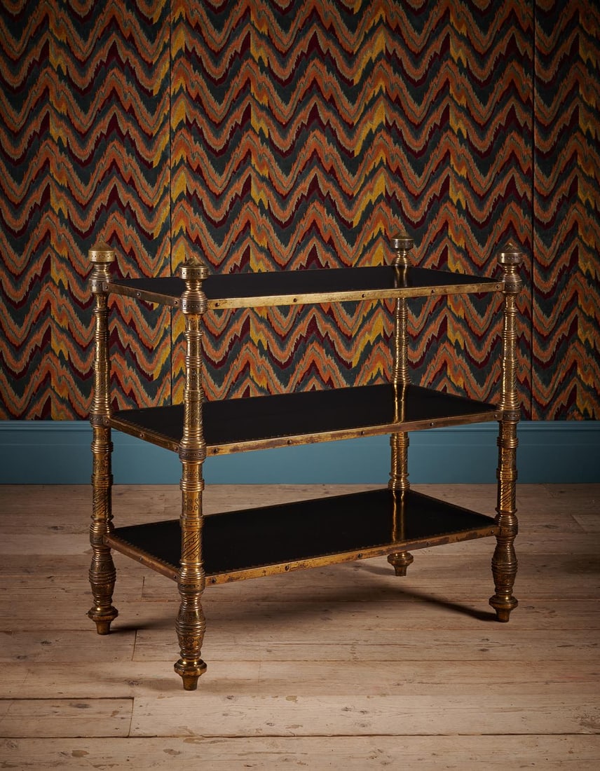 AN UNUSUAL AESTHETIC MOVEMENT EBONISED AND ENGRAVED GILT BRASS THREE TIER ETAGERE: AN UNUSUAL AESTHETIC MOVEMENT EBONISED AND ENGRAVED GILT BRASS THREE TIER ETAGEREIN THE MANNER OF BRUCE J. TALBERT, LATE 19TH OR EARLY 20TH CENTURY95.5cm high, 95cm wide, 49cm deepProvenance:The under