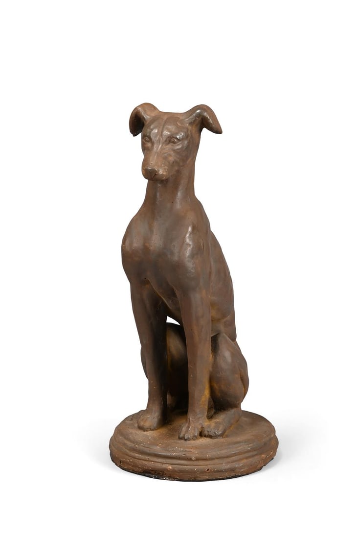 A BRONZED COMPOSITION STONE SEATED WHIPPET DOOR STOP OR DOOR PORTER, 20TH CENTURY: A BRONZED COMPOSITION STONE SEATED WHIPPET DOOR STOP OR DOOR PORTER20TH CENTURYModelled seated and alert43.5cm high, the base 21cm diameterFor a similar cast iron greyhound door porter, see Sotheby's 