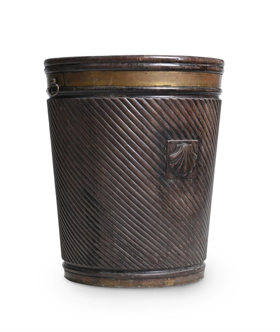 A LARGE CARVED MAHOGANY AND BRASS BOUND PEAT BUCKET, IN GEORGE III STYLE, 20TH CENTURY: A LARGE CARVED MAHOGANY AND BRASS BOUND PEAT BUCKET IN GEORGE III STYLE, 20TH CENTURY With a brass liner and a carved shell motif91cm high, 77cm diameter