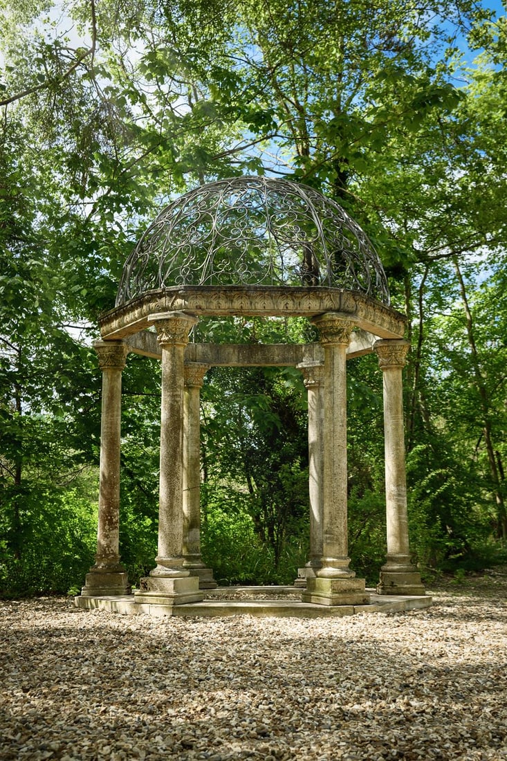 A LARGE WROUGHT IRON MOUNTED COMPOSITION STONE FOLLY OF CLASSICAL ROTUNDA FORM, 20TH CENTURY (1 of 2)
