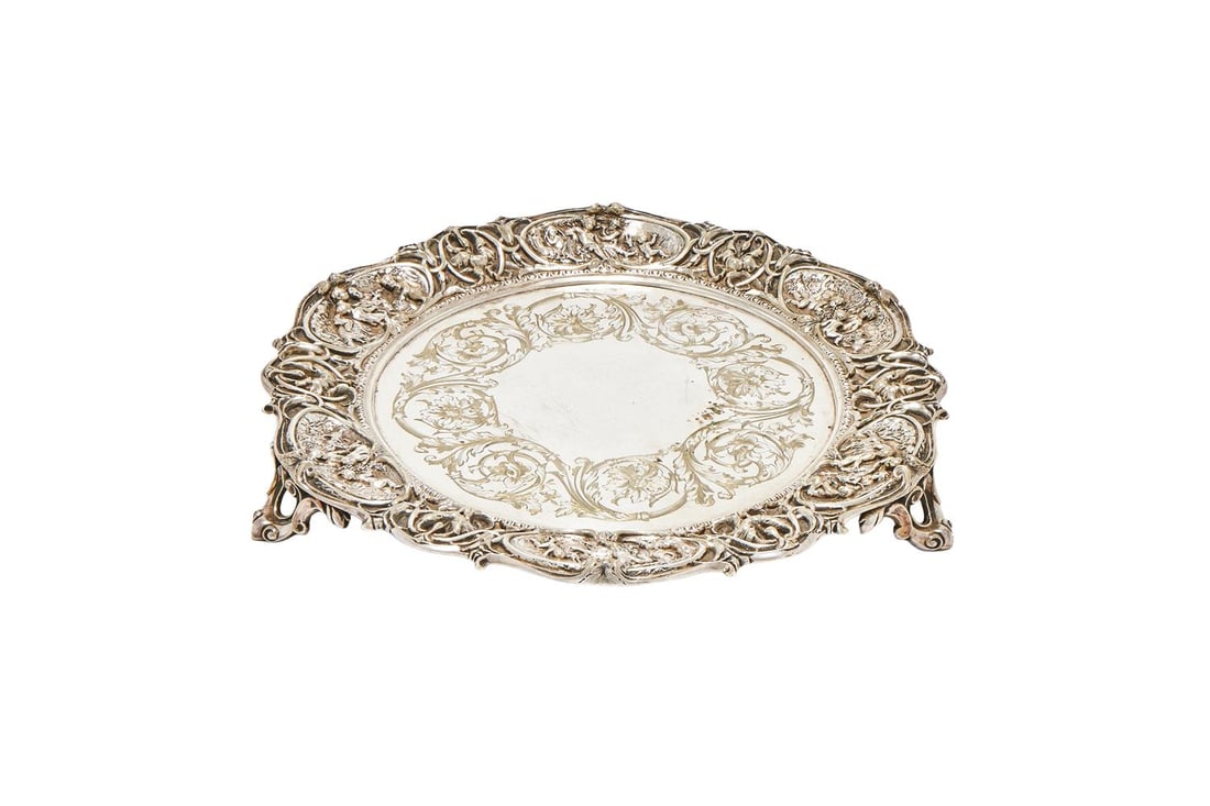 AN ELECTRO-PLATED SHAPED CIRCULAR SALVER: AN ELECTRO-PLATED SHAPED CIRCULAR SALVER MAKER'S MARK T. B. & S. The border chased with panel of putti in oval reserves and foliage, engraved with a foliate swag and floral band, on three