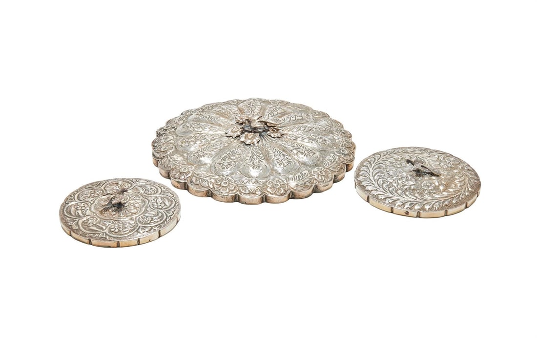 THREE EGPTIAN SILVER MOUNTED MIRRORS: AN EGYPTIAN SILVER SHAPED CIRCULAR MIRROR .900 STANDARD, 20TH CENTURY With a bird finial, chased with flowers and foliage 23.5cm diameter Together with: AN EGYPTIAN SILVER SHAPED CIRCULAR MIRROR POST