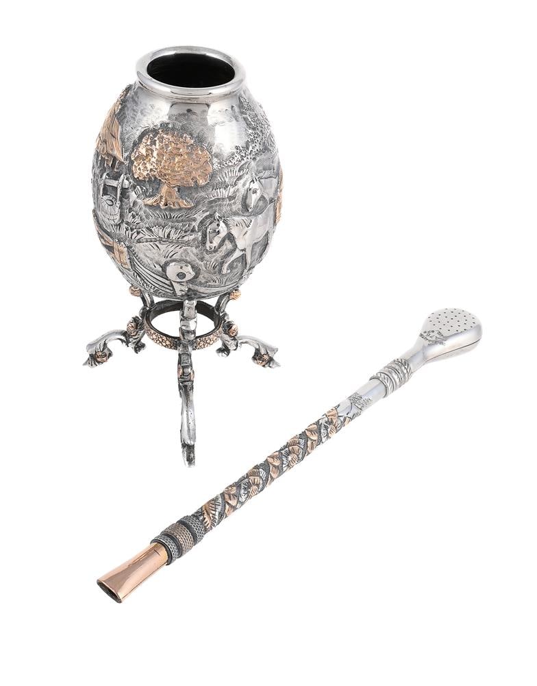 AN ARGENTINIAN SILVER BOMBILLA STRAW AND YERBA MATE GOURD: AN ARGENTINIAN SILVER BOMBILLA STRAW AND YERBA MATE GOURD The straw stamped 925 and 750, chased with a band of flowers, 20cm long The gourd with a figure on horseback riding through a farm, on three