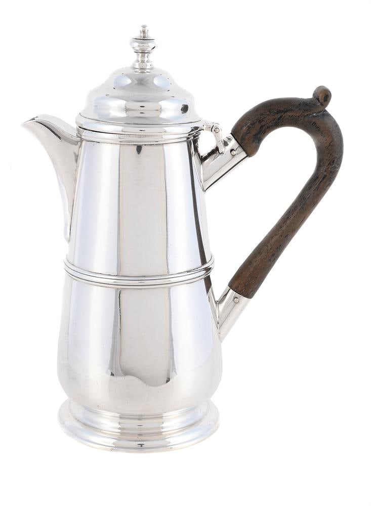 AN EDWARDIAN SILVER HOT WATER JUG: AN EDWARDIAN SILVER HOT WATER JUG D. & J. WELBY, LONDON 1907 With an orb finial to the ogee domed cover, a wood scroll handle, a girdle and on a circular moulded spreading foot 17.5cm high 329g