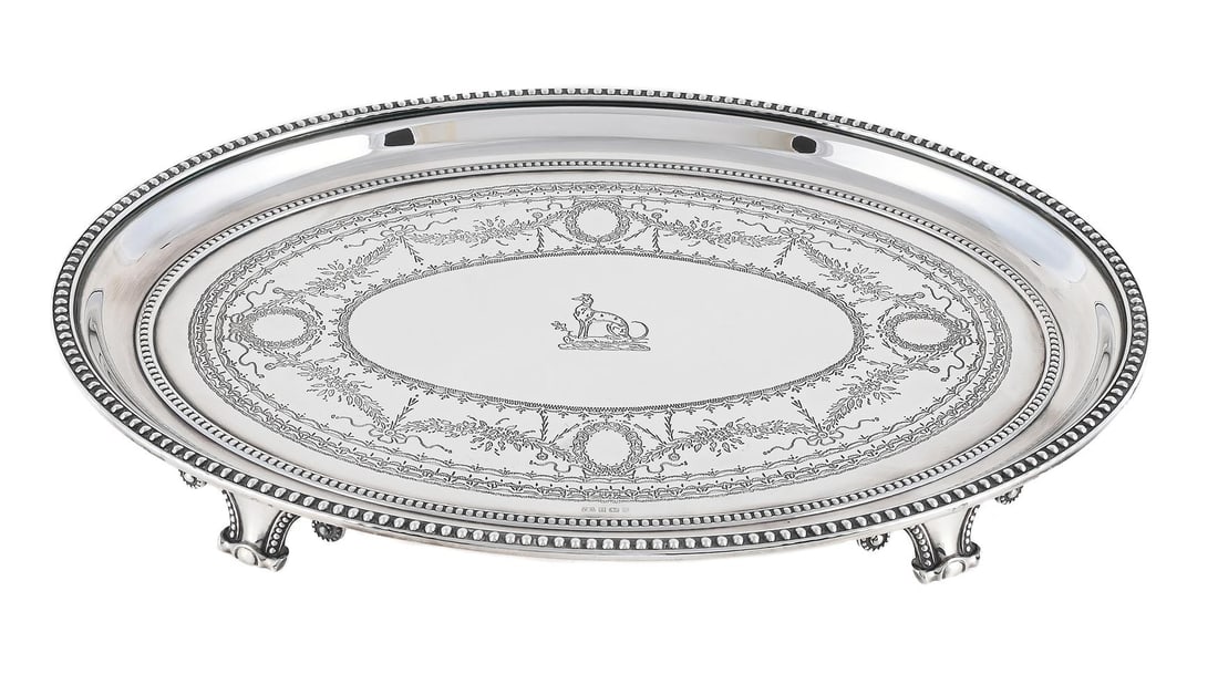 A SILVER OVAL TRAY: A SILVER OVAL TRAY VICTORIA SILVERWARE LTD., BIRMINGHAM 1996 With a beaded border, engraved with a crest, a floral swag, ribbon and wreath band, on four beaded scroll feet, engraved beneath 'To