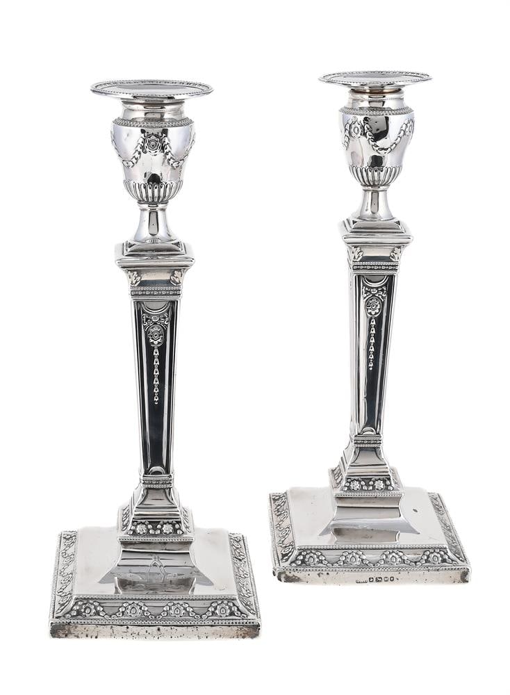 A PAIR OF VICTORIAN SILVER CANDLESTICKS: A PAIR OF VICTORIAN SILVER CANDLESTICKS HAWKSWORTH, EYRE & CO., SHEFFIELD 1855 With beaded circular sconces, urn shaped capitals, tapering square stems and on square bases, chased with husk swags