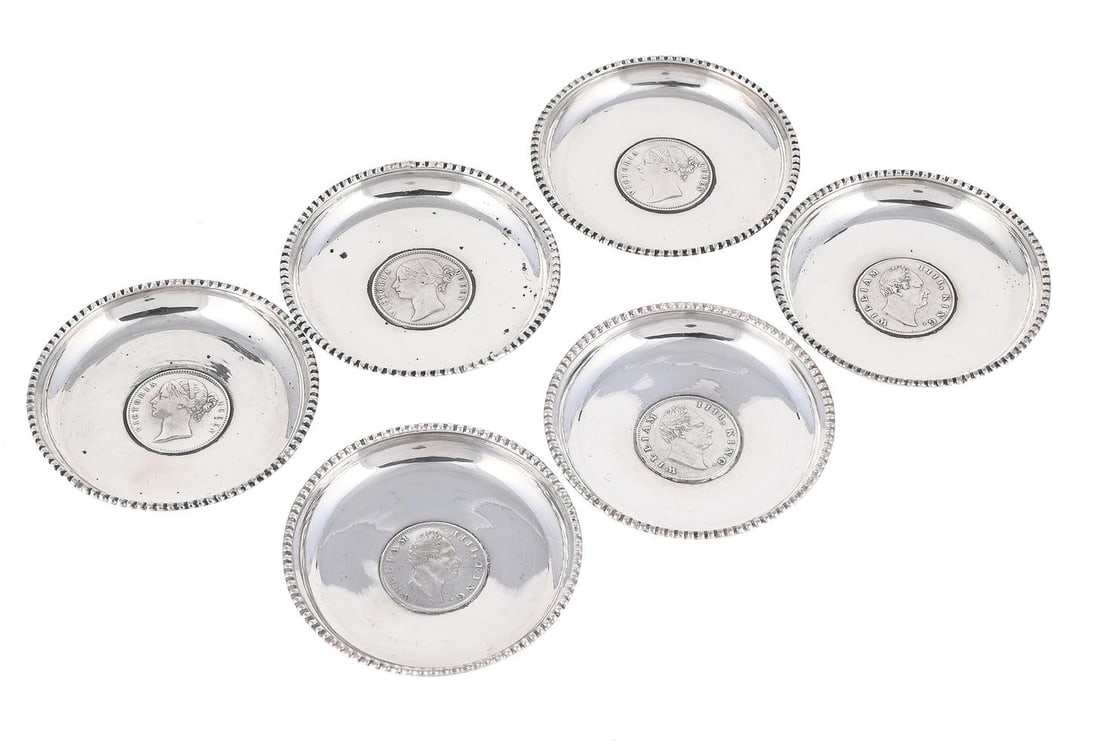 A SET OF SIX SILVER CIRCULAR DISHES: A SET OF SIX SILVER CIRCULAR DISHES STAMPED SILVER Each inset with a One Rupee coin 8.5cm diameter 293g (9.4 oz)