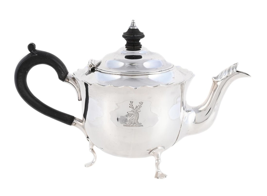 A VICTORIAN SILVER BACHELOR'S TEAPOT: A VICTORIAN SILVER BACHELOR'S TEAPOT MAPPIN & WEBB, LONDON 1896 With a wood finial to the ogee domed cover and scroll handle, a shaped border, engraved with a crest and on three trefoil pad