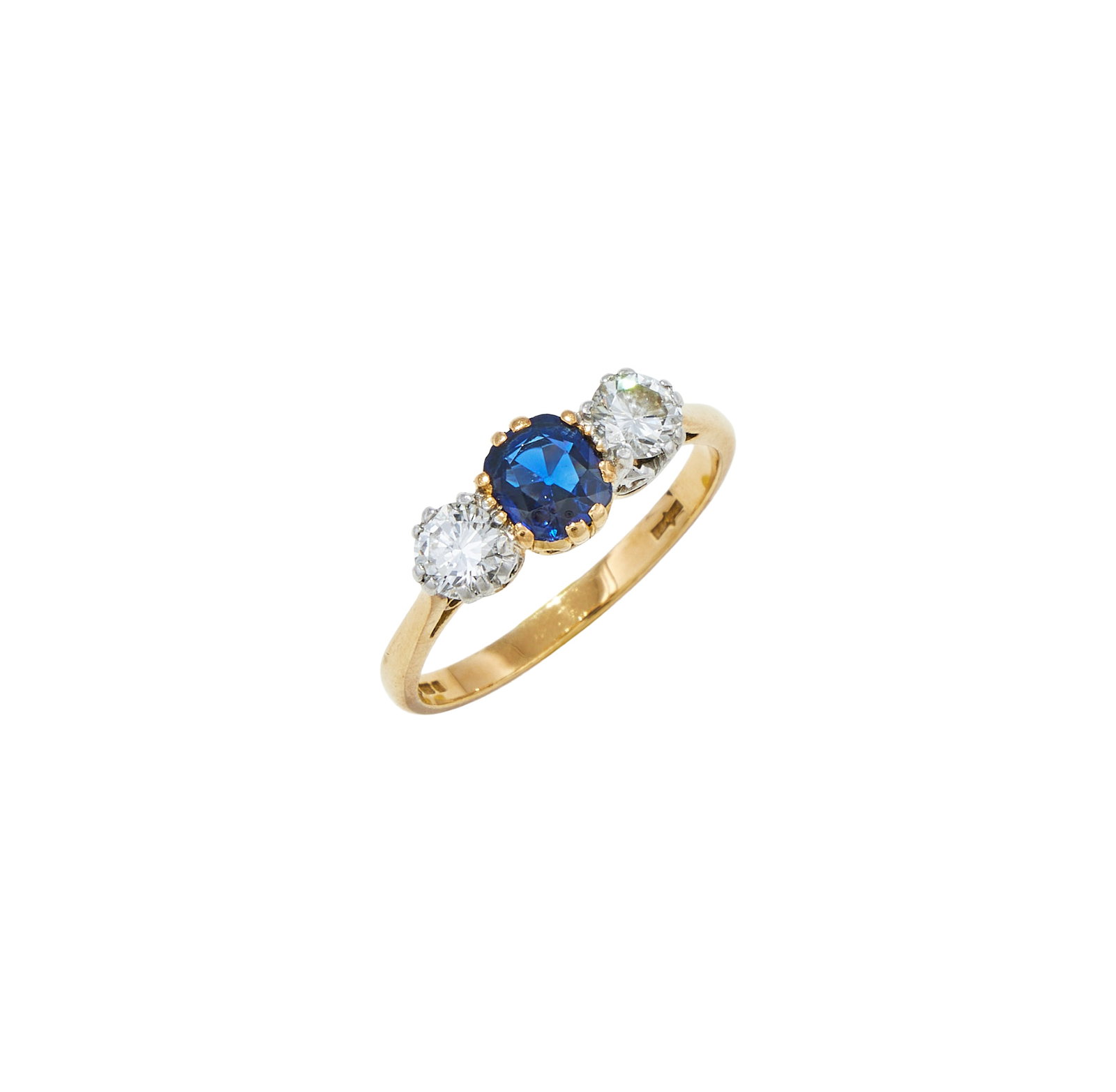 A SAPPHIRE AND DIAMOND THREE STONE RING: A SAPPHIRE AND DIAMOND THREE STONE RING The cushion shaped sapphire between brilliant cut diamond shoulders, to an 18ct gold shank, UK hallmark Size/dimensions: ring size O Gross weight: 3.6 grams