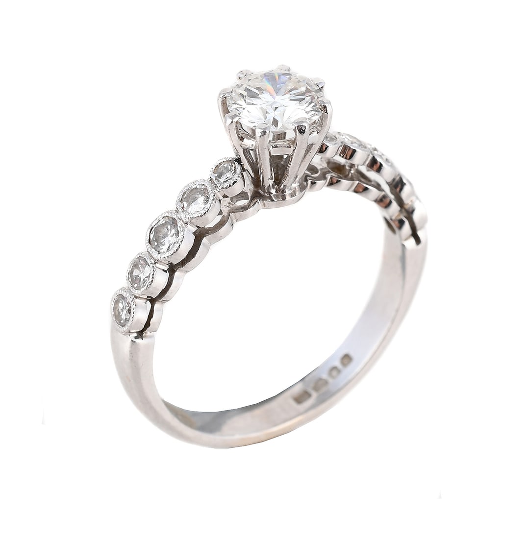 A DIAMOND SINGLE STONE RING: A DIAMOND SINGLE STONE RING The brilliant cut diamond claw set above millegrain set brilliant cut diamond shoulders, mounted in 18 carat white gold, UK hallmark Size/di