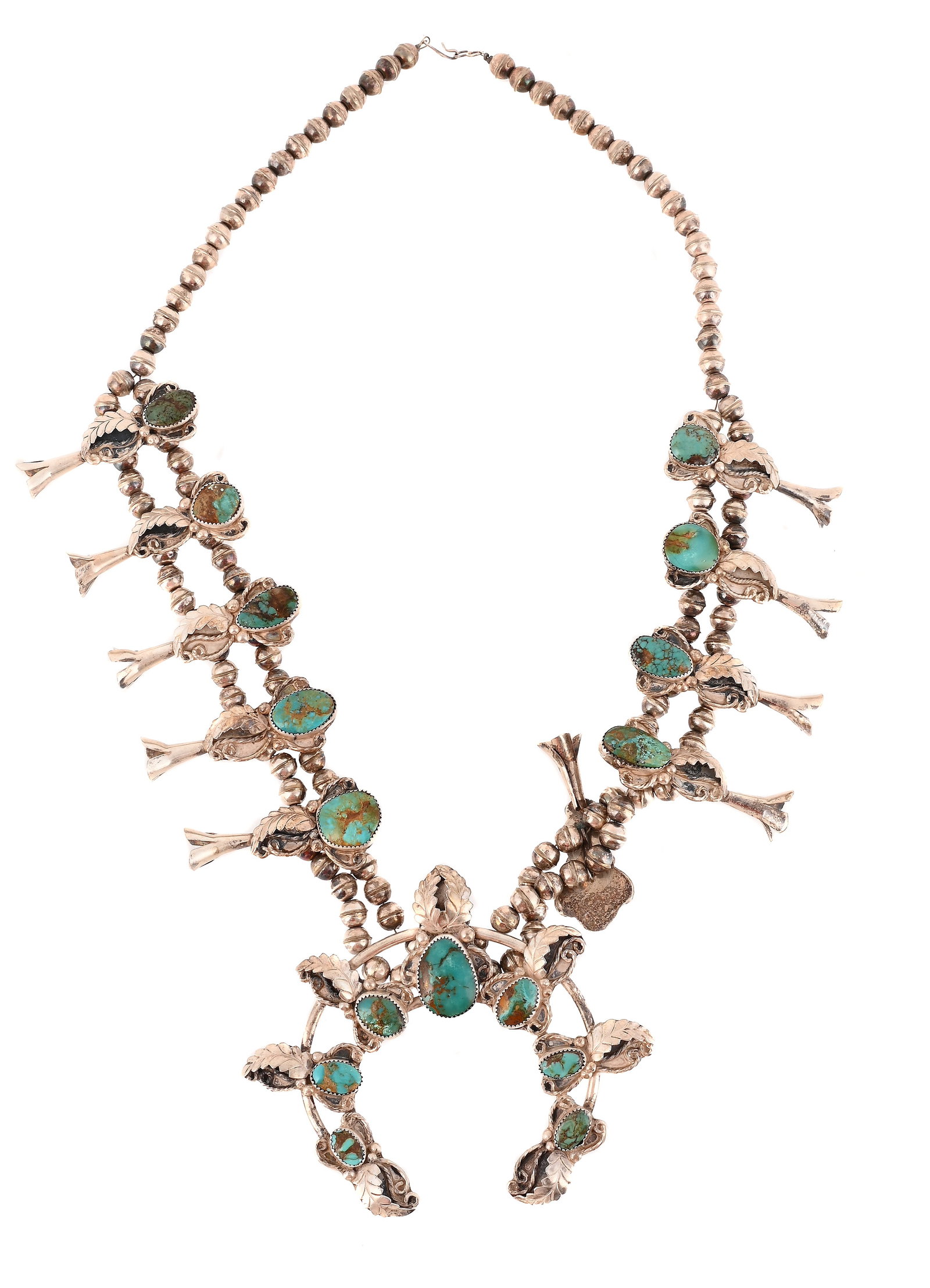 A TURQUOISE SQUASH BLOSSOM NECKLACE: A TURQUOISE SQUASH BLOSSOM NECKLACE The naja set with graduated oval turquoise matrix within cut claw settings, to ropetwist, beaded and curved leaf decorated surrounds, the necklace with