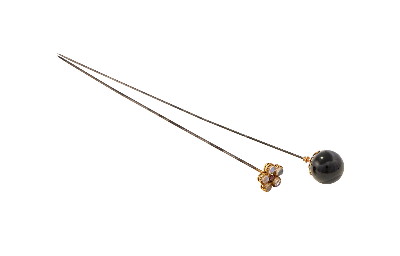 A VICTORIAN MOONSTONE AND RUBY HATPIN AND AN ONYX HATPIN: A VICTORIAN MOONSTONE AND RUBY HATPIN AND AN ONYX HATPIN The first with a cushion shaped ruby within a surround of five cabochon moonstones, to a base metal pin, unmarked; the second with a polished