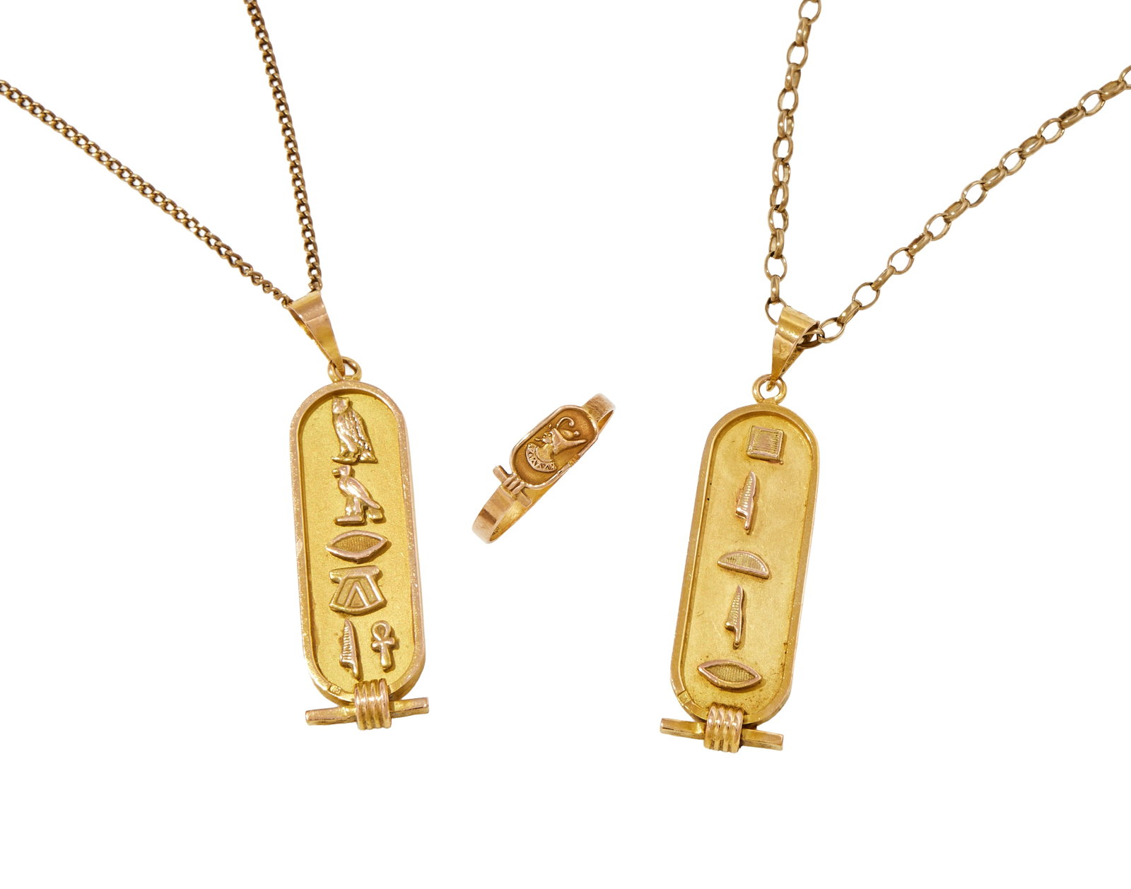 TWO EGYPTIAN DESIGN PENDANTS AND A RING: TWO EGYPTIAN DESIGN PENDANTS AND A RING The ring with an Atum wearing the Pschent; each pendant designed as an oval plaque with raised hieroglyphs on a matt ground, stamped with Egyptian