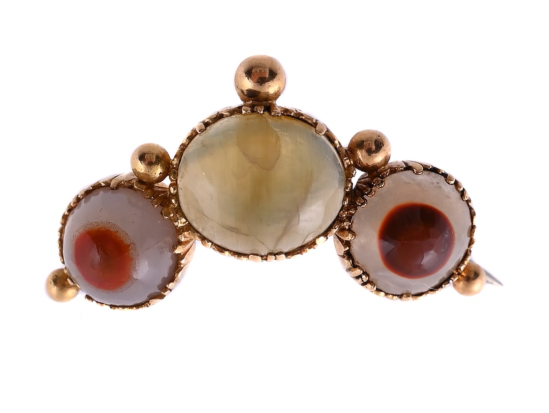 AN EARLY 19TH CENTURY CAT'S EYE CHRYSOBERYL AND AGATE BROOCH: AN EARLY 19TH CENTURY CAT'S EYE CHRYSOBERYL AND AGATE BROOCH The oval cabochon cat's eye chrysoberyl between two cabochon banded onyx, in a cut down gold setting, unmarked Size/dimensions: 2.5cm wide