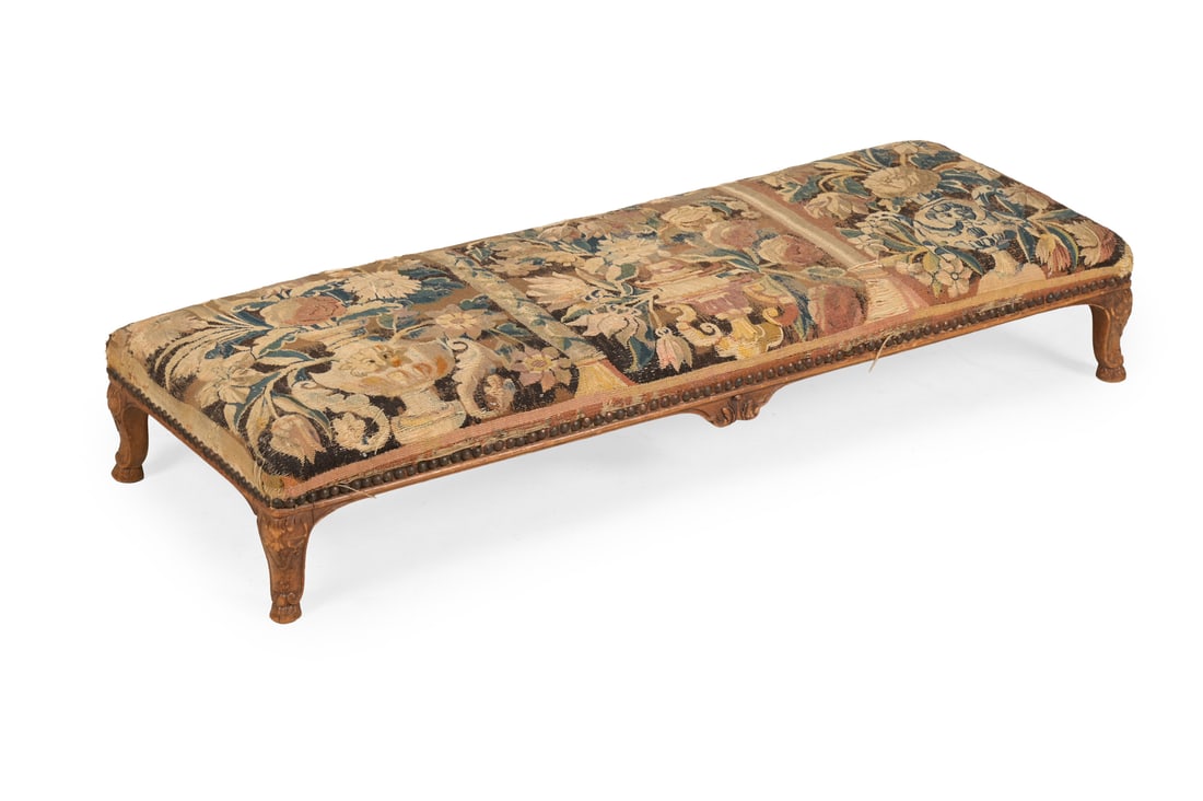 A CARVED BEECH AND TAPESTRY UPHOLSTERED LONG STOOL, IN LOUIS XV STYLE, LATE 19TH CENTURY: A CARVED BEECH AND TAPESTRY UPHOLSTERED LONG STOOLIN LOUIS XV STYLE, LATE 19TH CENTURYUpholstered in 18th century verdure tapestry with three flowering urns18cm high, 107cm long, 38.5cm wide