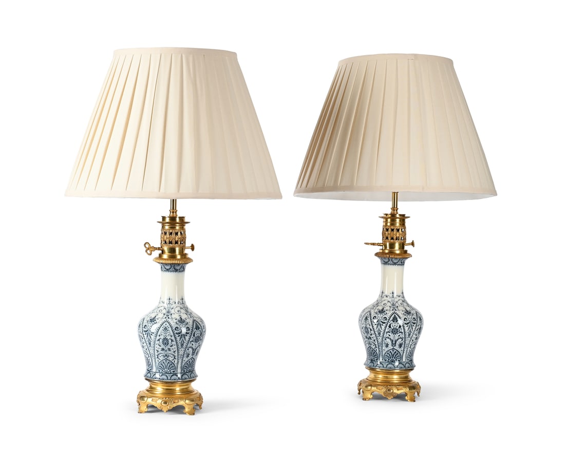 A PAIR OF FRENCH GILT METAL MOUNTED BLUE AND WHITE PORCELAIN VASE TABLE LIGHTS, LATE 19TH CENTURY: A PAIR OF FRENCH GILT METAL MOUNTED BLUE AND WHITE PORCELAIN VASE TABLE LIGHTS LATE 19TH CENTURY Fitted for electricity and with pleated silk shades, PAT tested 39cm high excluding fitment, 71cm high 