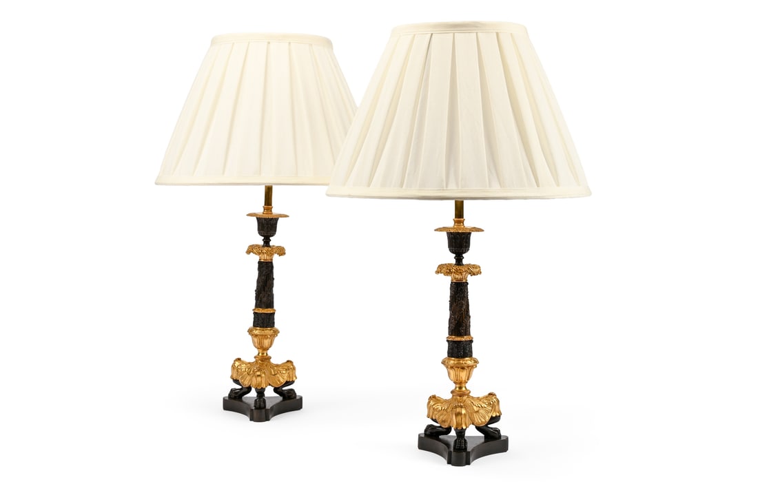 A PAIR OF BRONZE AND GILT CANDLESTICK TRIFORM TABLE LIGHTS, SECOND HALF 19TH CENTURY: A PAIR OF BRONZE AND GILT CANDLESTICK TRIFORM TABLE LIGHTSSECOND HALF 19TH CENTURYLater fitted for electricity with pleated shades, unwired32cm high to top of candlestick, 58cm high overall including 