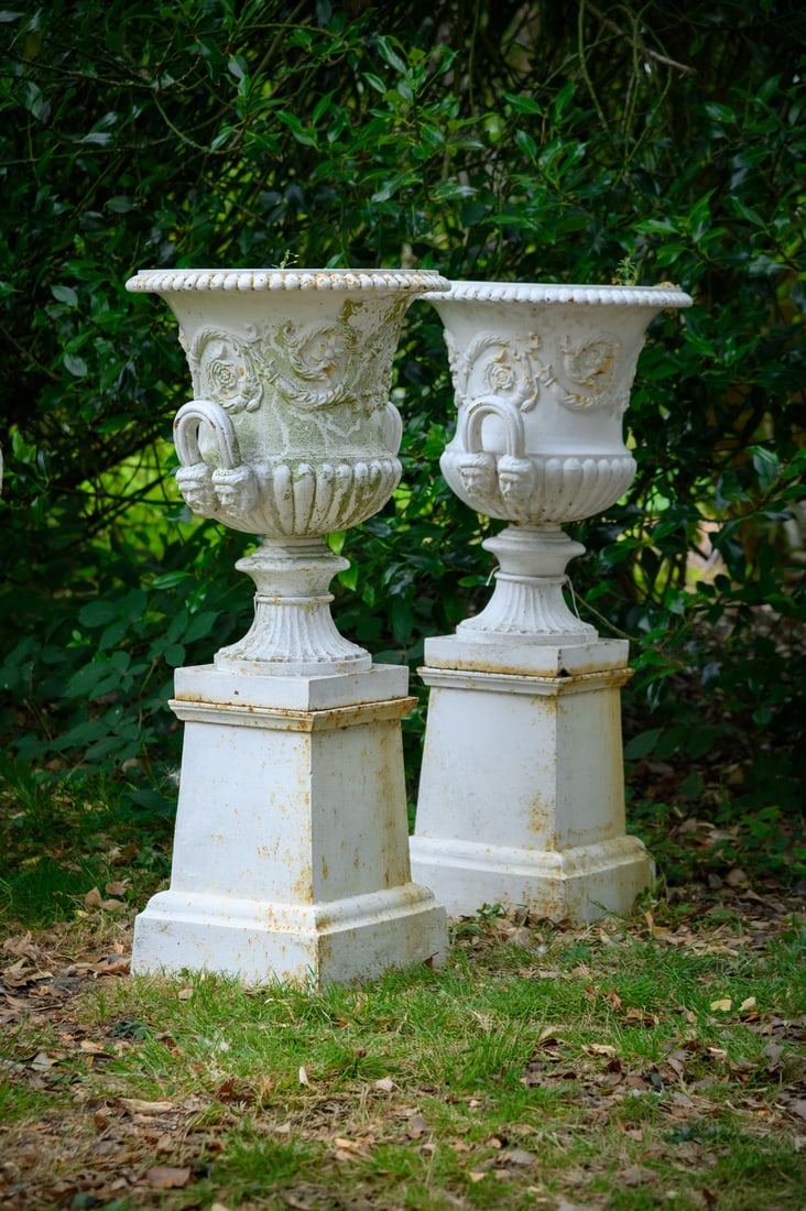 A PAIR OF HANDYSIDE WHITE PAINTED CAST IRON URNS ON STANDS, 19TH CENTURY: A PAIR OF HANDYSIDE WHITE PAINTED CAST IRON URNS ON STANDS 19TH CENTURYthe urns 61cm high, the tops 46cm diameterthe stands 39cm high, 32cm square 100cm high overall