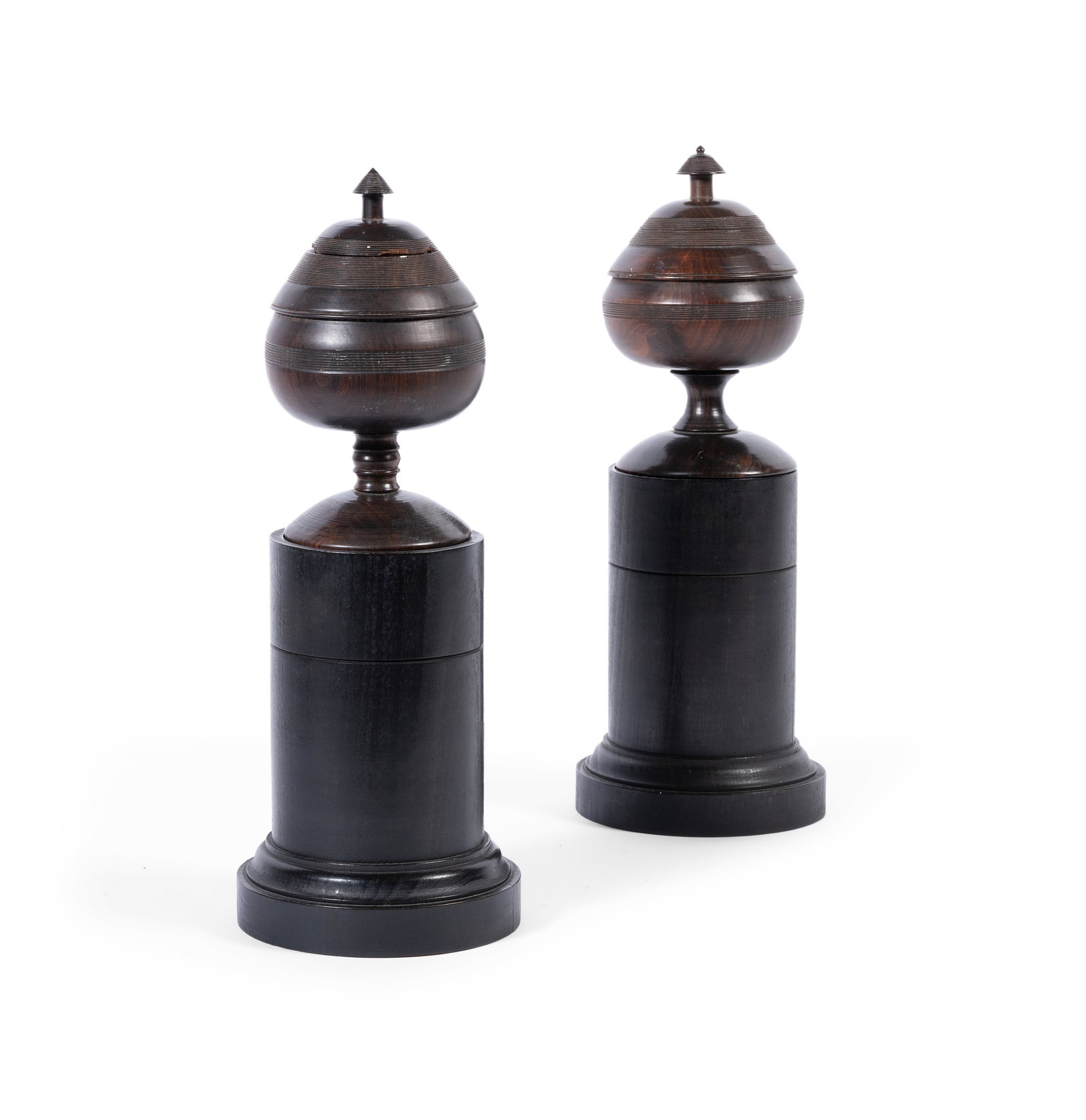 A PAIR OF AFRICAN BLACK WOOD URNS ON PAINTED PEDESTALS BY GEORGE OAKES, 20TH CENTURY: A PAIR OF AFRICAN BLACK WOOD URNS ON PAINTED PEDESTALS BY GEORGE OAKES 20TH CENTURY The urns 17cm high, 36cm high overall Photographed in ‘Colefax & Fowler’, Chester Jones, Barrie
