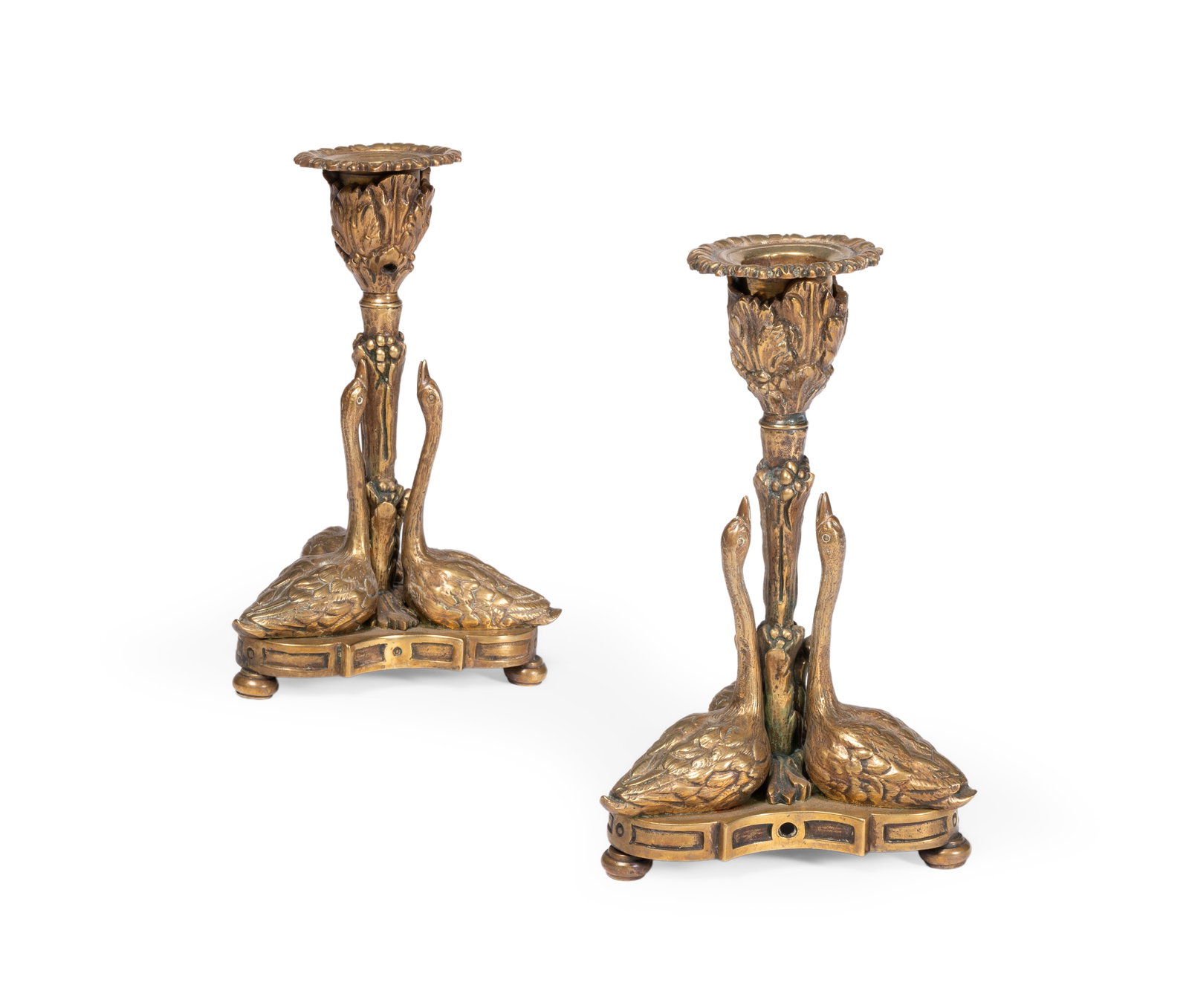 A PAIR OF BRASS CANDLESTICKS, IN GEORGE IV STYLE, FIRST HALF 20TH CENTURY: A PAIR OF BRASS CANDLESTICKS, IN GEORGE IV STYLE AFTER A DESIGN BY RUNDELL, BRIDGE AND RUNDELL, FIRST HALF 20TH CENTURY each with a leaf decorated socket above a triform base modelled with three