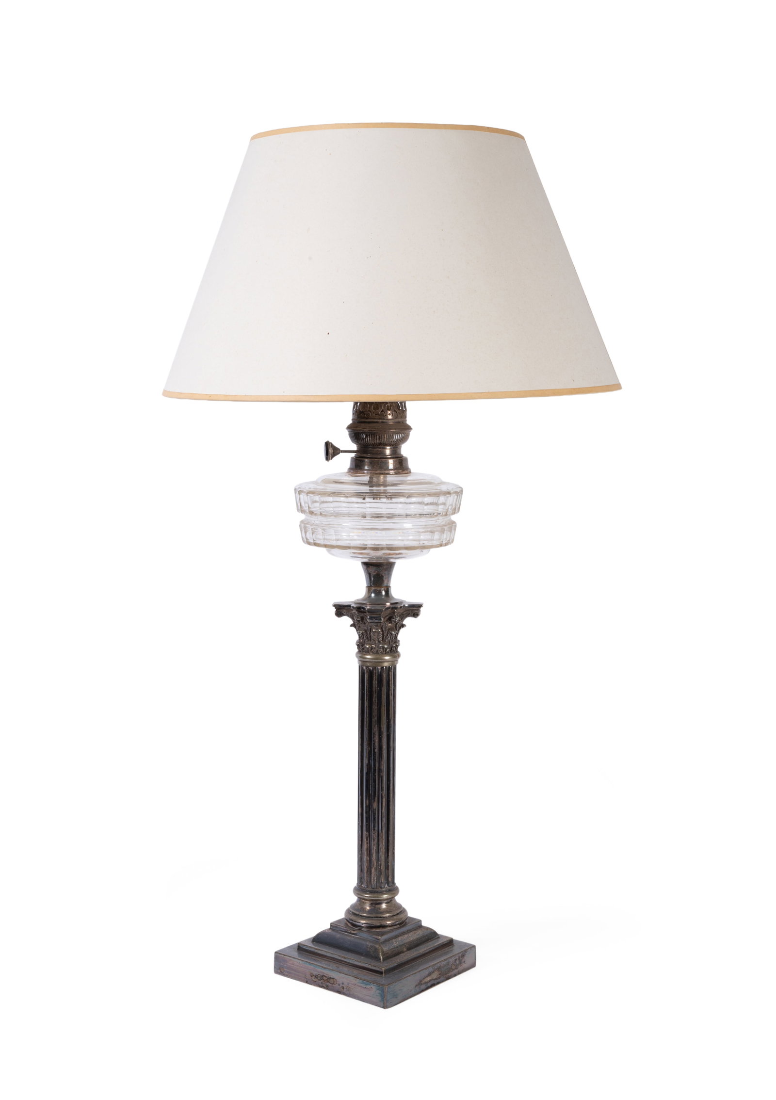 A LATE VICTORIAN GLASS AND SILVER PLATED CORINTHIAN COLUMN TABLE LAMP, LATE 19TH CENTURY: A LATE VICTORIAN GLASS AND SILVER PLATED CORINTHIAN COLUMN TABLE LAMP LATE 19TH CENTURY Originally an oil lamp now fitted to electricity, with card shade 83cm high overall Condition Report Disclaimer